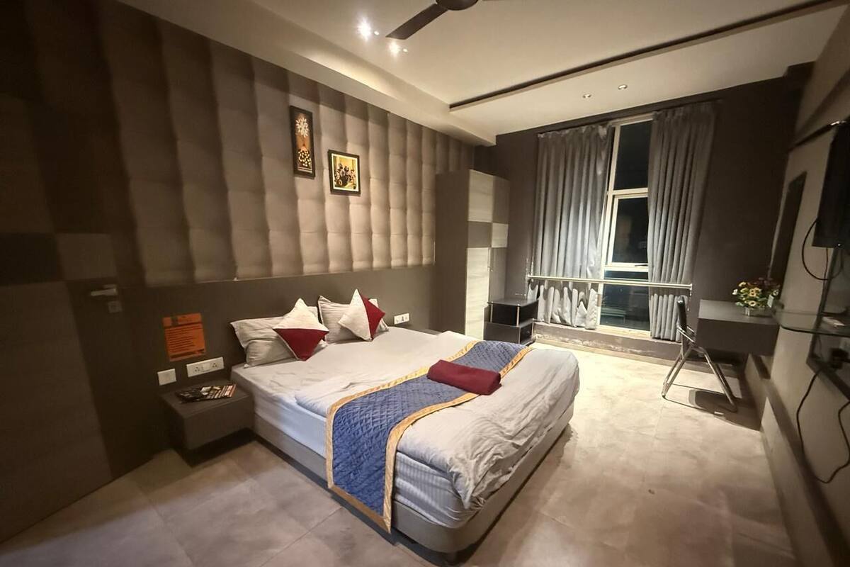 Een moderne slaapkamer met een groot bed, nachtkastjes, een raam met gordijnen en uitzicht op het omliggende landschap.