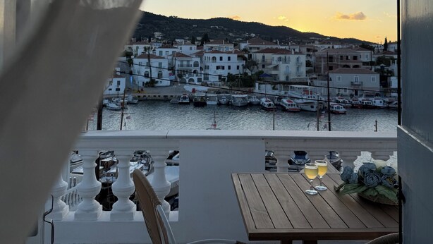 Ein Balkon mit Blick auf einen Hafen, ein Tisch mit Stühlen und eine Lampe.