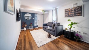 Un salon moderne avec un canapé gris, un tapis blanc et un buffet noir.