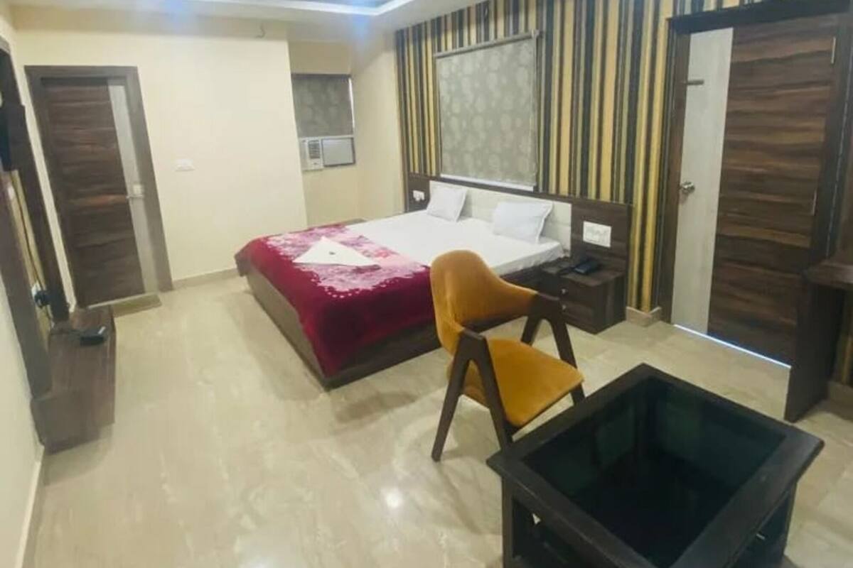 Una habitación de hotel con cama, una silla, una mesita, ventilador de techo y papel tapiz a rayas.