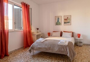 A bedroom with a bed, a nightstand, a small table, and two wall-mounted paintings. - Casa Nina - Al Massimo: Cozy loft in the historic center of Palermo (Palermo)