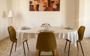 A dining table set for four with a white tablecloth, two chairs, and a painting on the wall. - Casa Nina - Al Massimo: Cozy loft in the historic center of Palermo (Palermo)