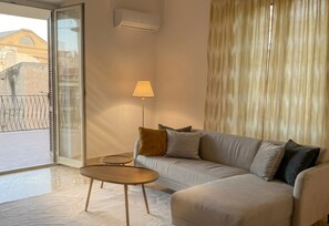 A modern living room with a sofa, a small round table, a floor lamp, and a sliding glass door leading to an outdoor area. - Casa Nina - Al Massimo: Cozy loft in the historic center of Palermo (Palermo)