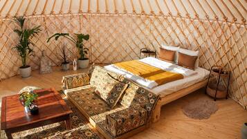 Um ambiente acolhedor com cama, sofá e plantas em vasos.