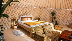 A cozy room with a bed, a sofa, a small table, and a decorative lamp. - WOODMOOD yurt with wellness (Leuk)