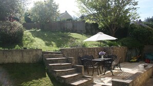 Une terrasse avec une table, des chaises et un parasol blanc.