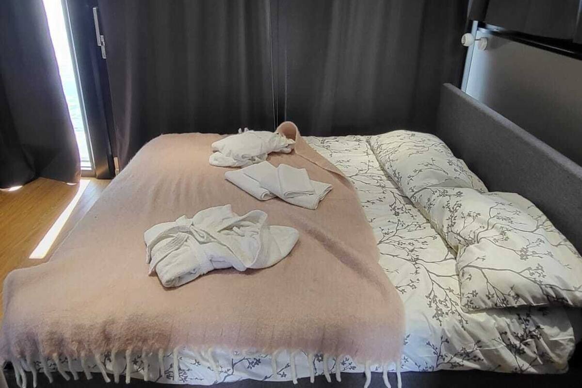 Quarto moderno com uma cama grande, cortinas escuras e vista para o exterior.