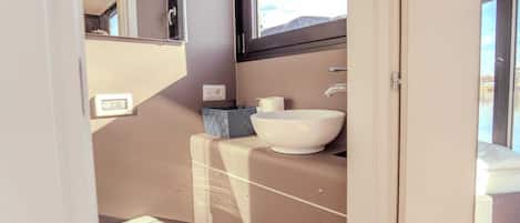 Un baño compacto con un lavamanos blanco, un pequeño cubo de basura y un inodoro.