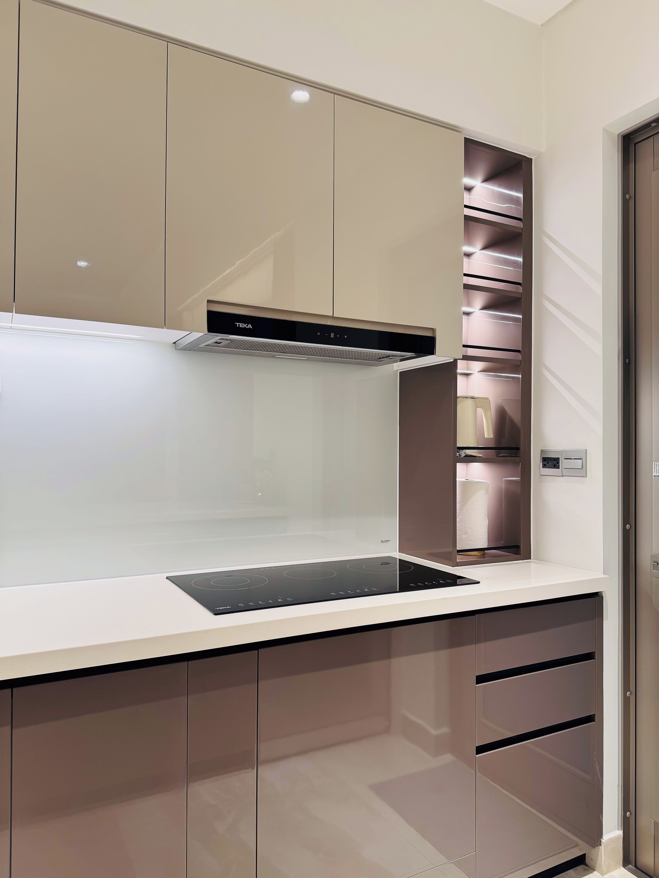A modern kitchen with a built-in stove, cabinets, and a stainless steel range hood.