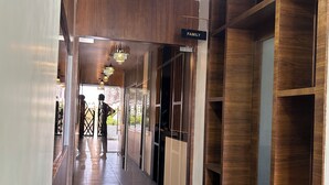 A hallway with a chandelier, wooden shelving, and a 'FAMILY' sign. - Hotel Chaufula Garden Lodging (Shirur)