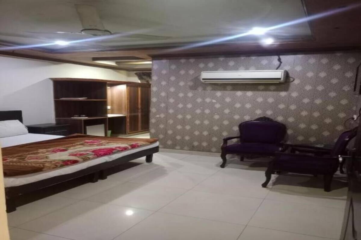 A bedroom with a bed, a wardrobe, a chair, and an air conditioning unit.