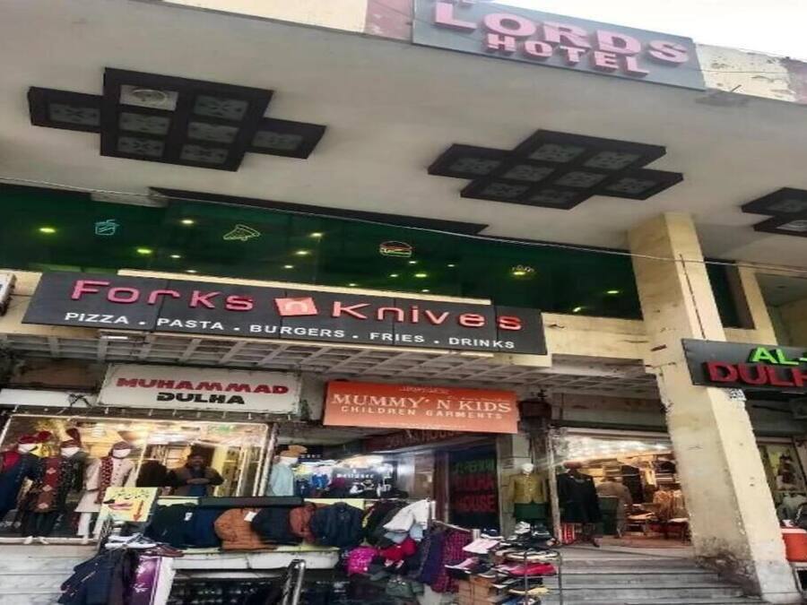 Ein Gebäude mit mehreren Geschäften, darunter eine Pizzeria, ein Bekleidungsgeschäft und ein Hotel.