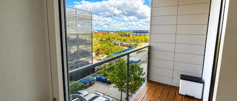 A balcony with a view of a parking lot and buildings.