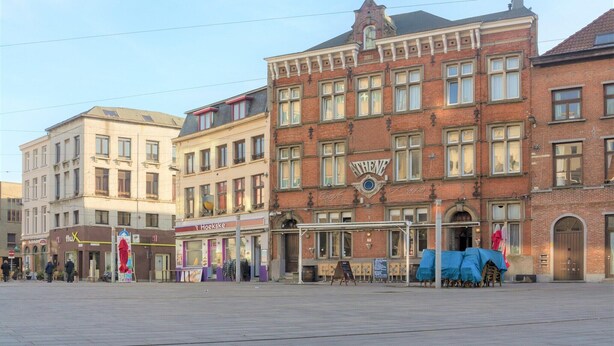 Eine Straße mit Gebäuden, darunter ein rotes Backsteingebäude mit dem Schild 'Athena'.