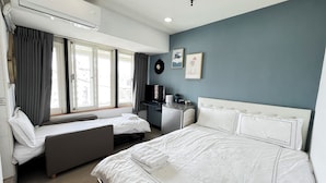 A hotel room with a bed, a sofa, a desk, an air conditioning unit, and a window with curtains. - STAG Haven (Taipei)