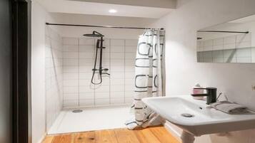A bathroom with a shower, a sink, and a mirror.