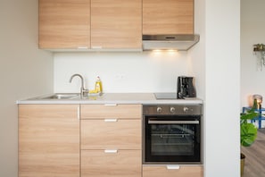 Una cocina moderna con armarios de madera, horno empotrado, cafetera y pileta.