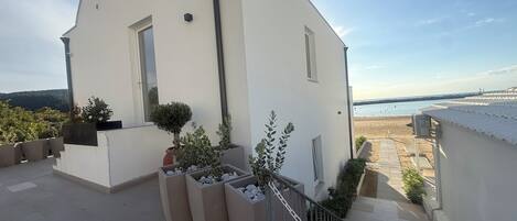 A white building with a balcony overlooking a beach.