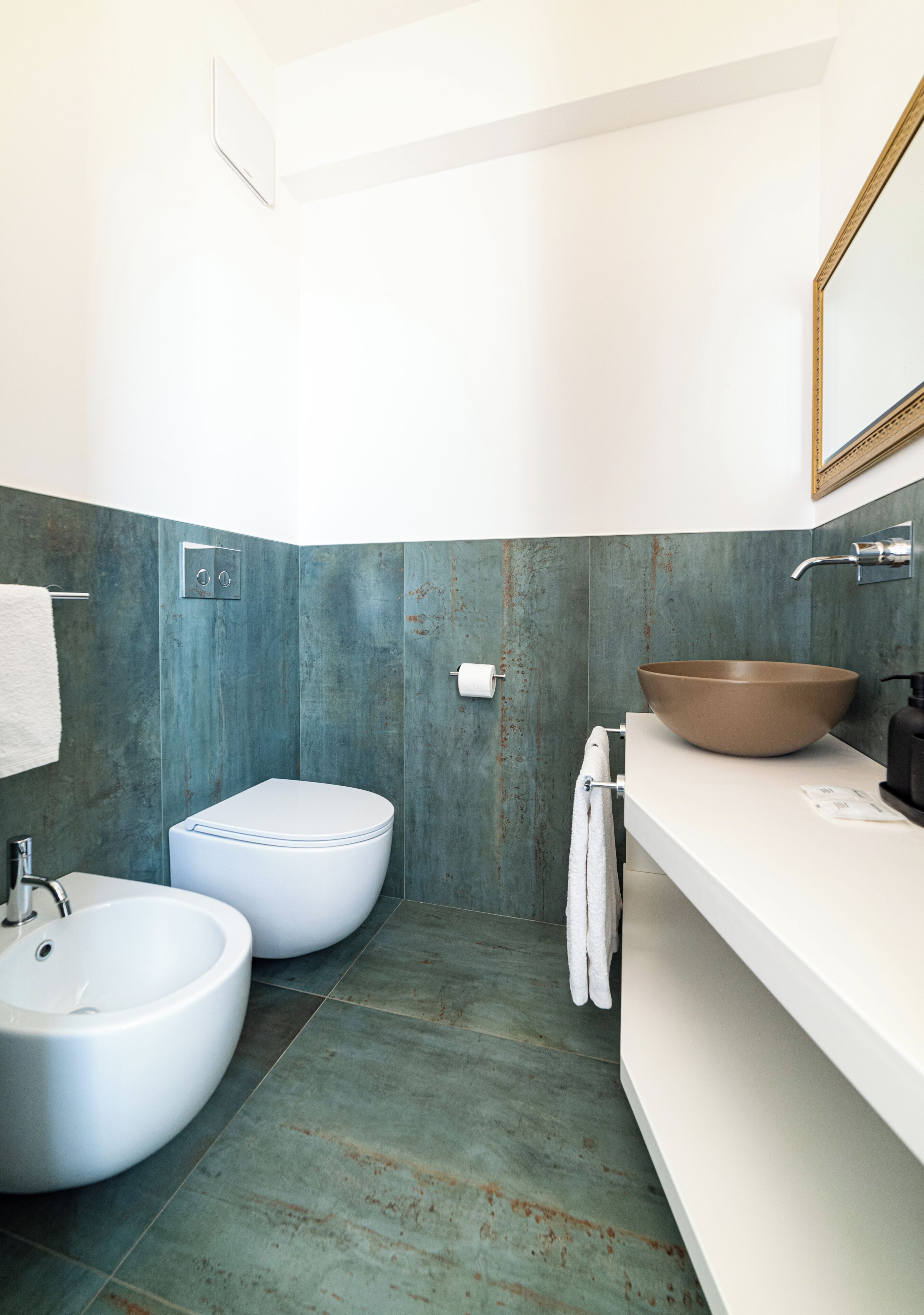 Uma casa de banho moderna com uma sanita branca, uma lavatório bege e uma toalha pendurada na parede.