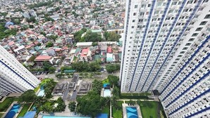 A high-rise residential building with multiple balconies, a swimming pool, and a well-maintained garden area. - Cozy 2-bedroom condo w/AC living room, balcony, Netflix walking dis to SM North (Quezon City)