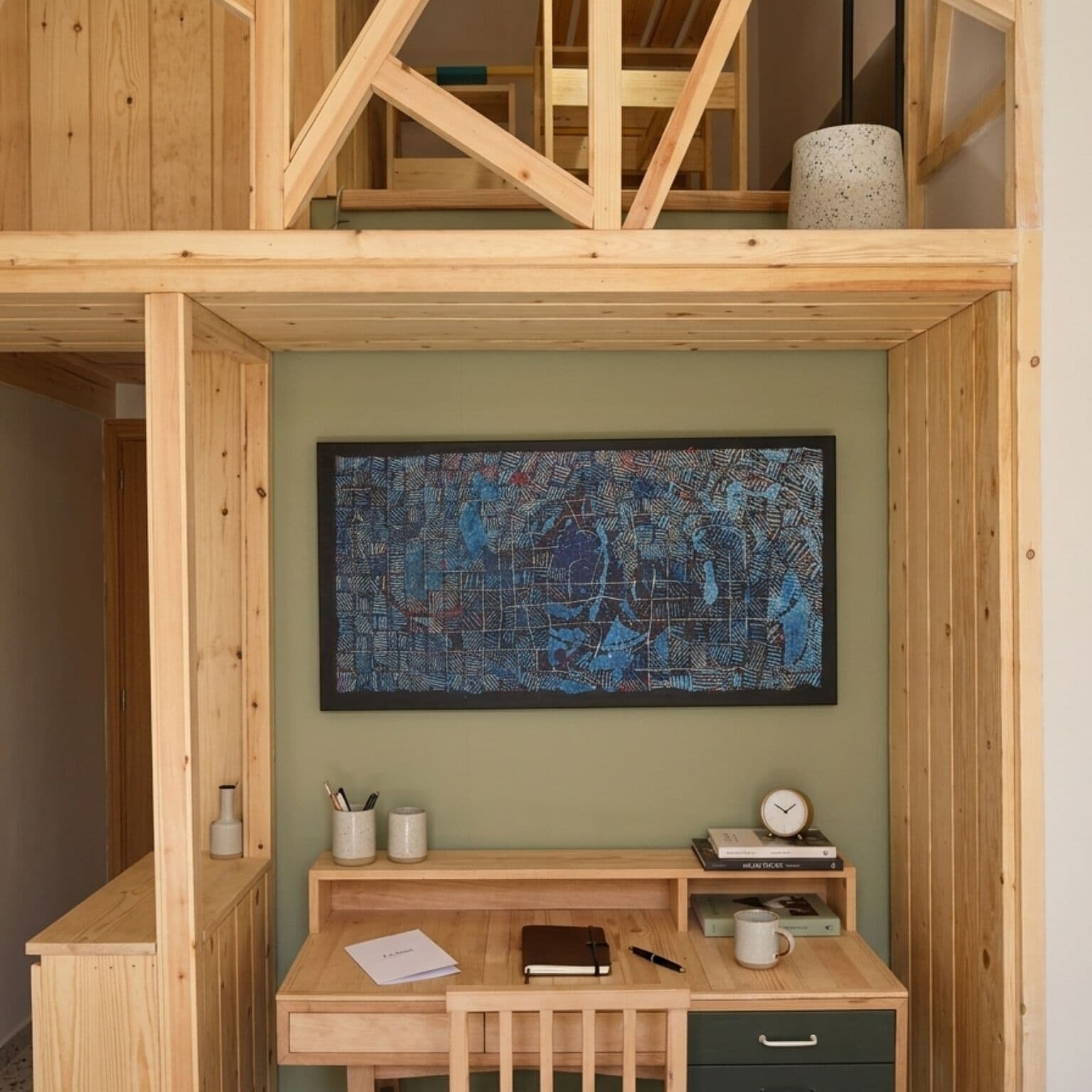 A wooden desk with a map artwork, a clock, and a cup.