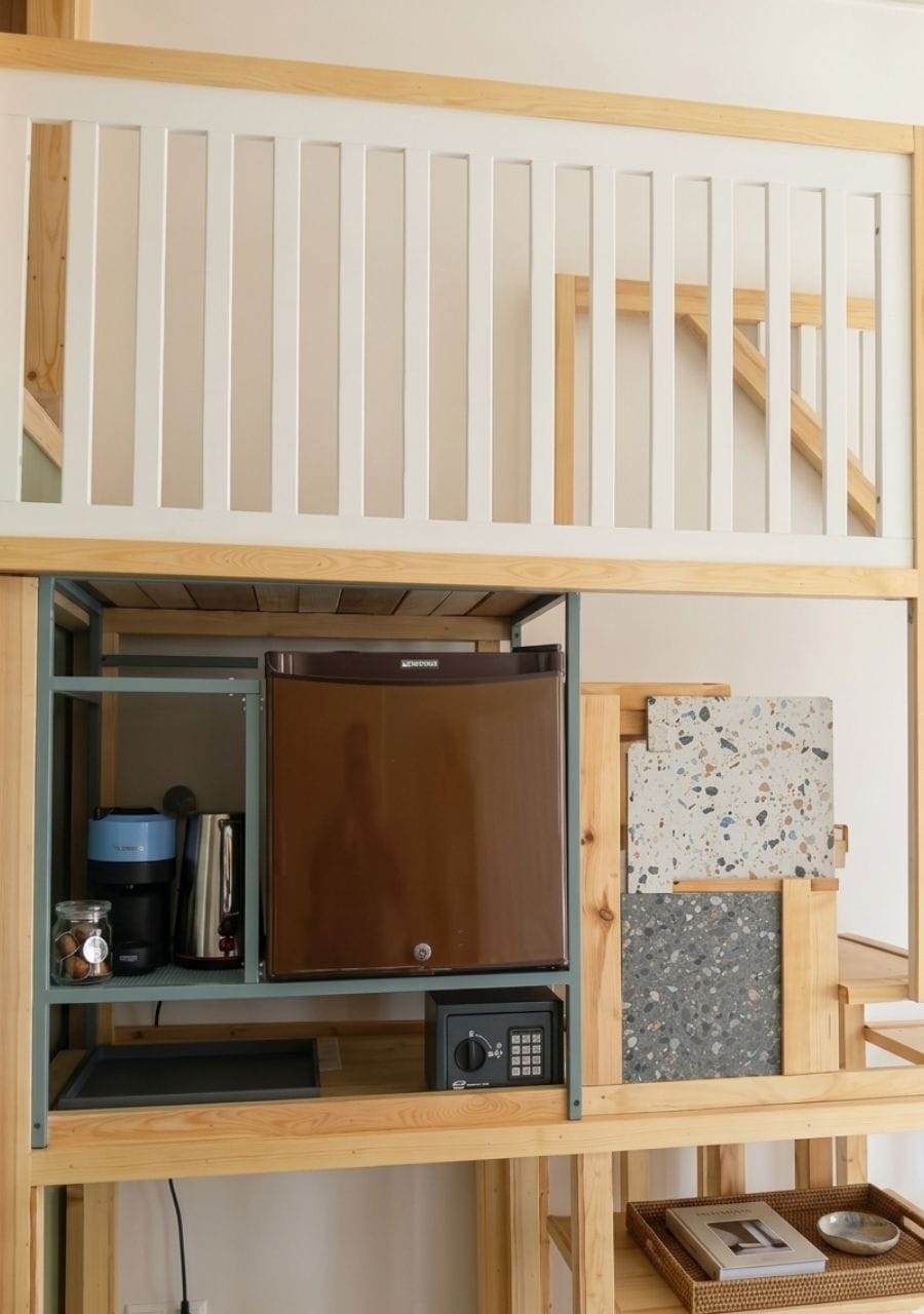 Un letto a castello con un angolo cottura sottostante, completo di frigorifero, forno a microonde e macchina del caffè.