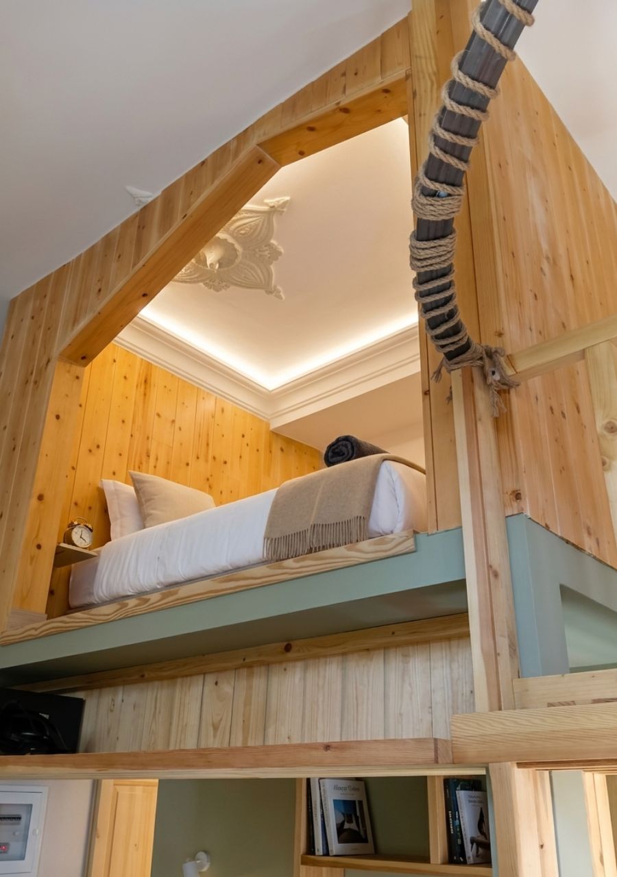 A bunk bed with a wooden headboard and a rope ladder.