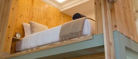 A bunk bed with a wooden headboard and a rope ladder.