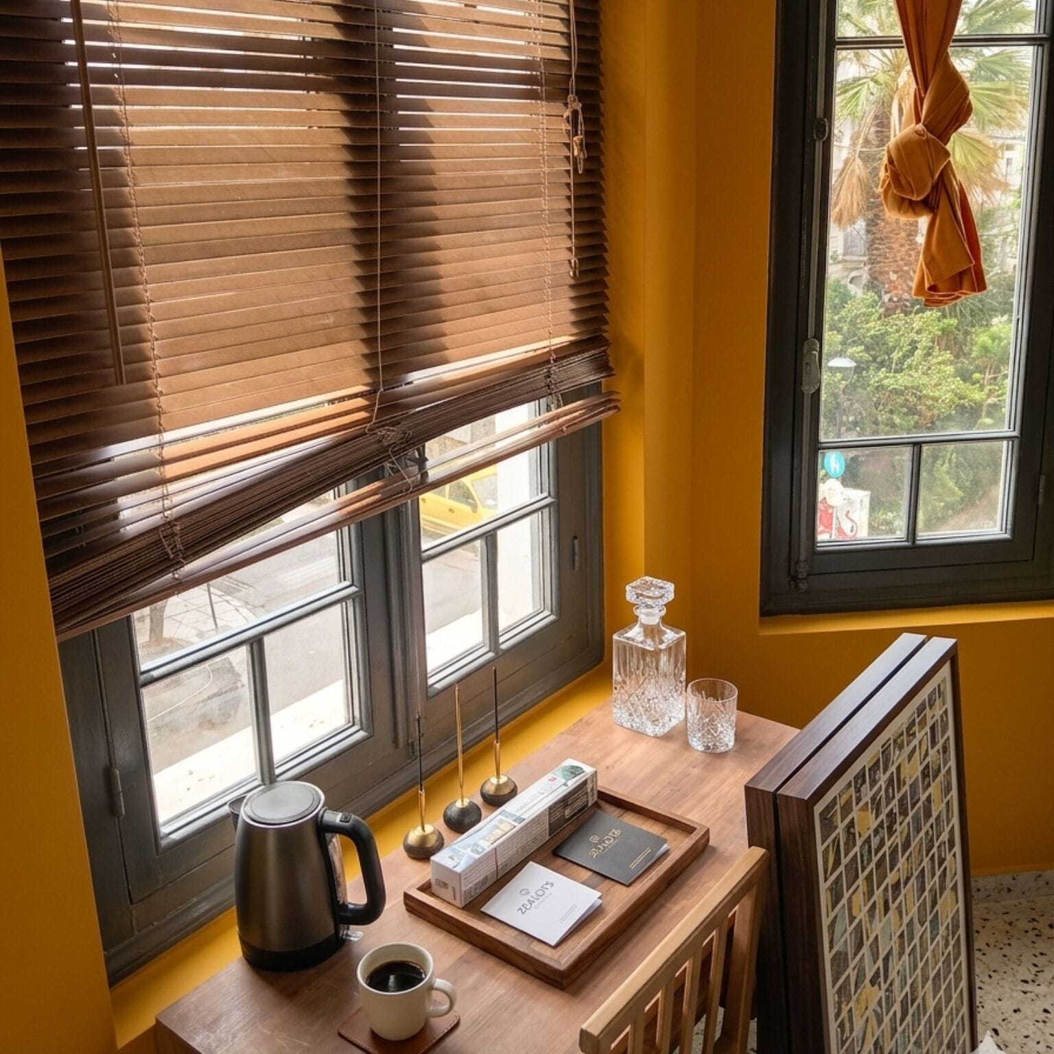 A room with a window, a radiator, a coffee table with a kettle, a cup, and a tray with items.