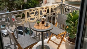 A balcony with two chairs, a table, and a potted plant.