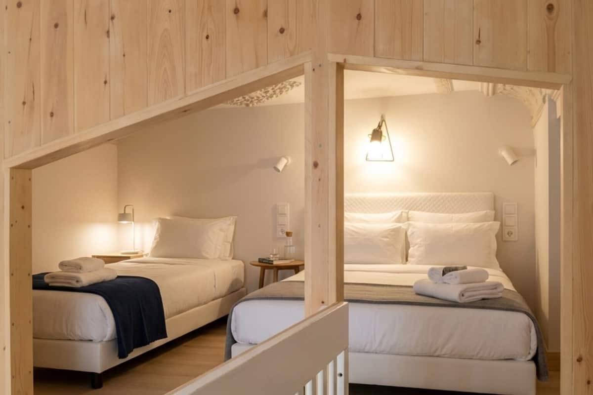 A hotel room with two beds, wooden walls, and a small table with a lamp.