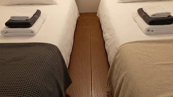 A hotel room with two beds, each with white linens and a folded towel.
