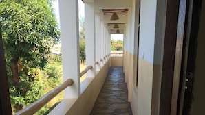 A corridor with a stone-patterned floor, white walls, and a wooden ceiling. - Simba Apartments Diani  (Ukunda)