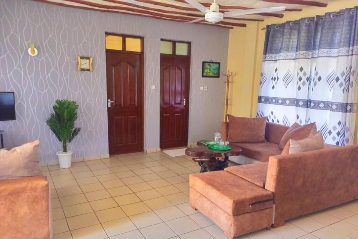 Una sala de estar con un sofá, un televisor, un ventilador de techo y una puerta.