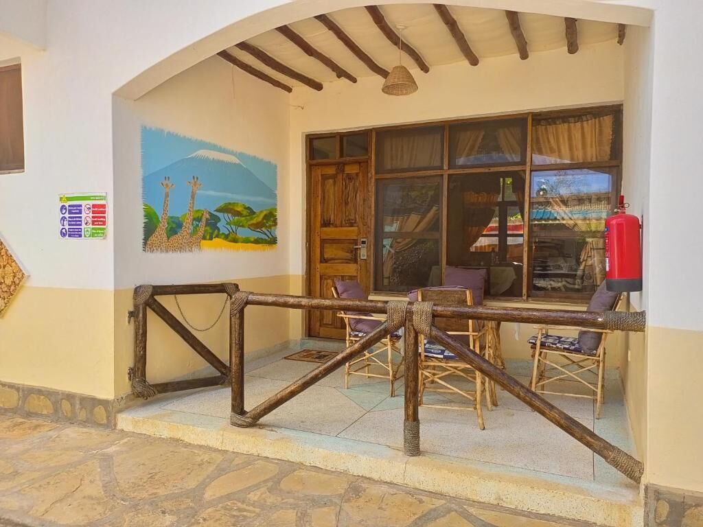 Quarto com porta de madeira, janela com cortinas, pintura de girafas e extintor de incêndio.