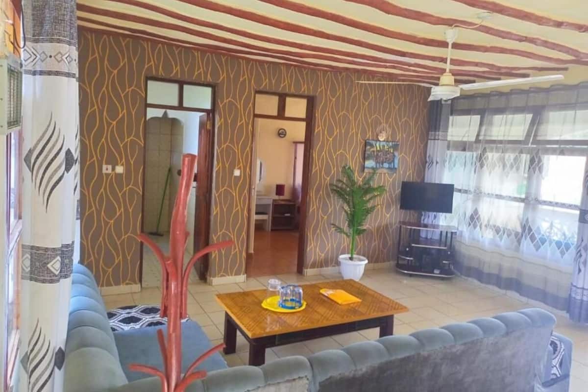 Una sala de estar con sofá, mesa de centro, televisión y ventilador de techo.