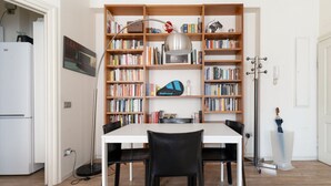 Ein Essbereich mit einem weißen Tisch, schwarzen Stühlen und einer Bücherwand voller Bücher.