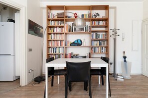 Ein Essbereich mit einem weißen Tisch, schwarzen Stühlen und einer Bücherwand voller Bücher.