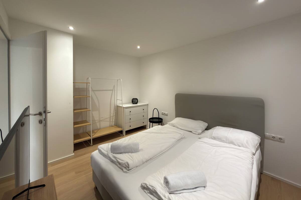 Une chambre à coucher comprenant un lit, une commode, une table de chevet et un placard avec un miroir.