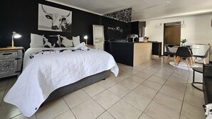 Une chambre à coucher moderne avec un grand lit, des tables de chevet, un bureau et une chaise.
