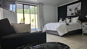 Une chambre d’hôtel moderne, équipée d’un lit, d’un canapé, d’une table basse en marbre et d’une grande fenêtre avec des rideaux.
