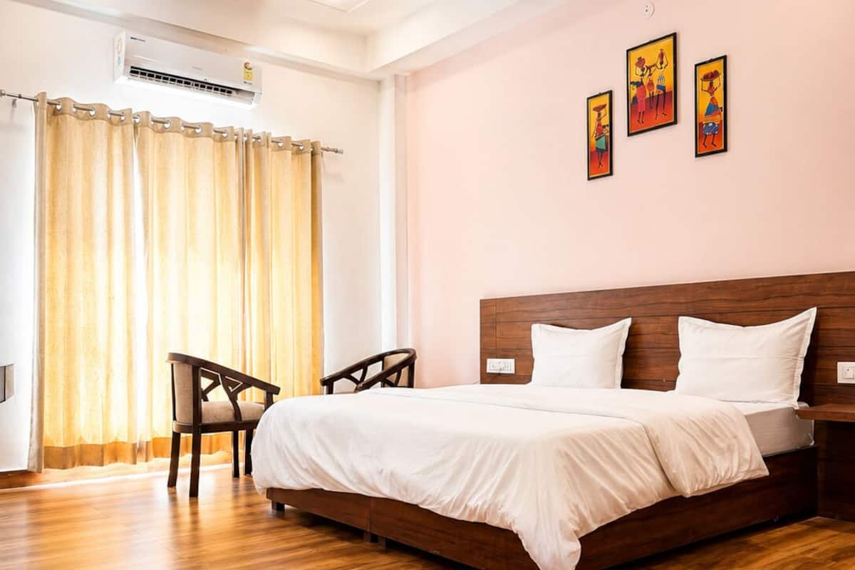 A bedroom with a bed, a chair, a ceiling fan, and artwork on the wall.