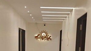 A hallway with a modern light fixture, a door on the right, and a window on the left.