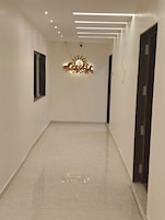 Un pasillo con una lámpara moderna, una puerta a la derecha y una ventana a la izquierda.