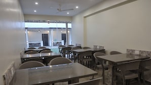 A modern dining area with multiple tables and chairs, a ceiling fan, and a view of the outdoor area.