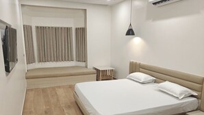 A bedroom with a bed, bedside tables, a TV, curtains, and a ceiling light.