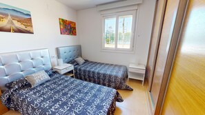 Ein Schlafzimmer mit zwei Betten, einem Fenster und einem Bild an der Wand.