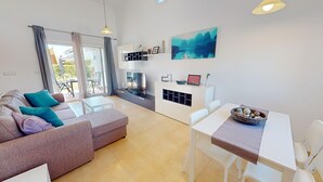 A modern living room with a sofa, a dining table, and a TV. - Villa - Stay6 - Garden - Parking - Pool - Golfarea (Torre-Pacheco)