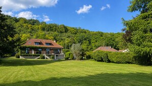 Ein Haus mit rotem Ziegeldach, umgeben von einem gepflegten Rasen und üppiger Bepflanzung.