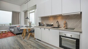 Eine moderne Küche mit weißen Schränken, einem eingebauten Backofen und einem großen Fenster.